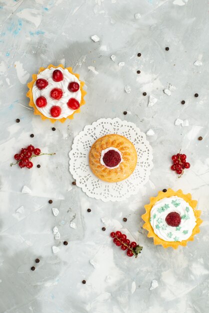 Top distant view little d cakes with cream and different fruits isolated on the light surface sugar sweet 