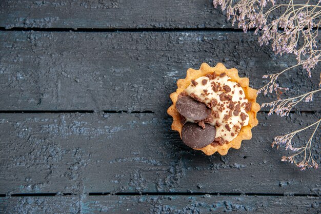 Top distant view tart with chocolate dried flower branch on dark wooden table