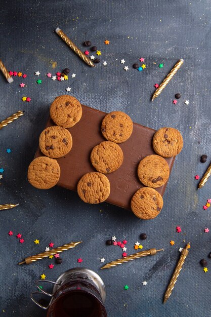 Top distant view yummy chocolate cookies on the brown case with tea candles on the dark-grey background cookie biscuit sweet tea