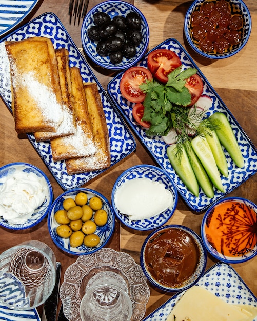 Free photo top  fresh salad with cucumbers herbs and tomatoes served with toasts and black olives on the table