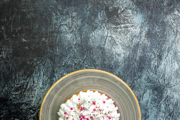 Top half view cake with pastry cream on grey round platter on grey table free space