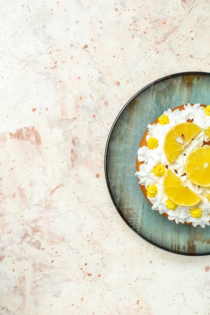 Top half view cake with white pastry cream and lemon slices on round plate