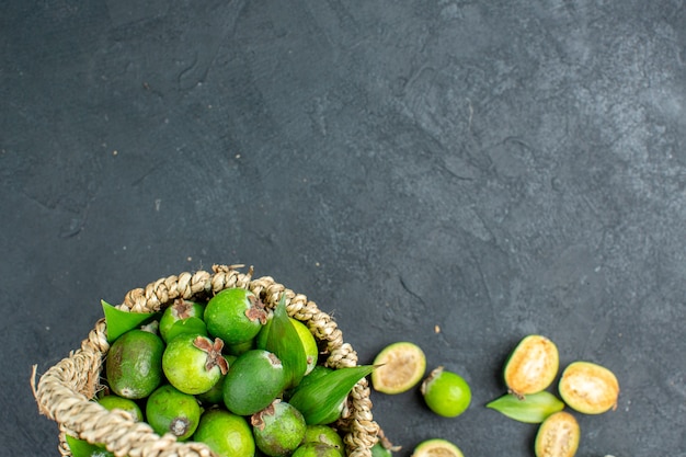 Free Photo top half view fresh feijoas in basket on dark surface free space