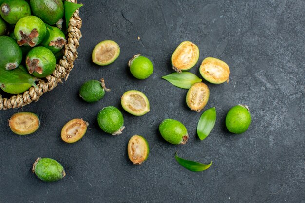 Top half view fresh feijoas in basket on dark surface