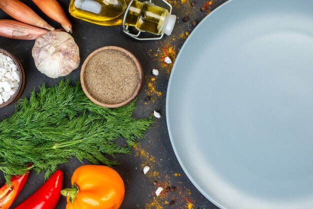 Top half view grey round platter fresh vegetables and other stuffs on dark