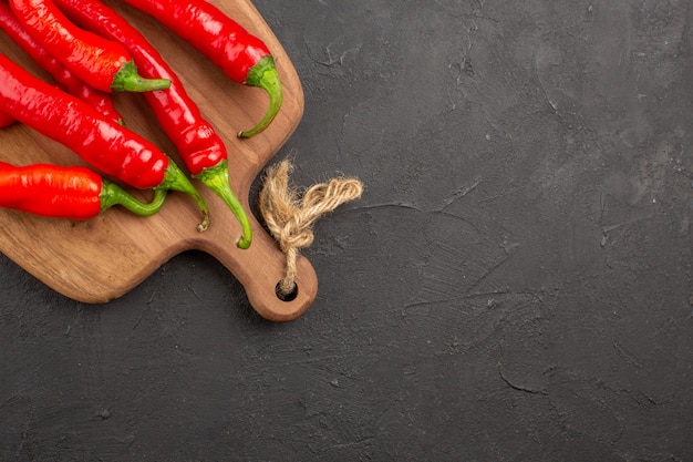 Top half view red hot peppers on a chopping board on the black table