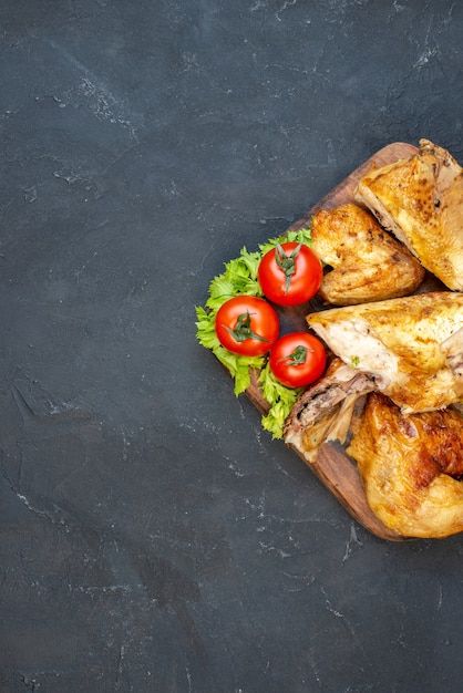 Free photo top half view roasted chicken tomatoes lemon slices on wooden board on black table