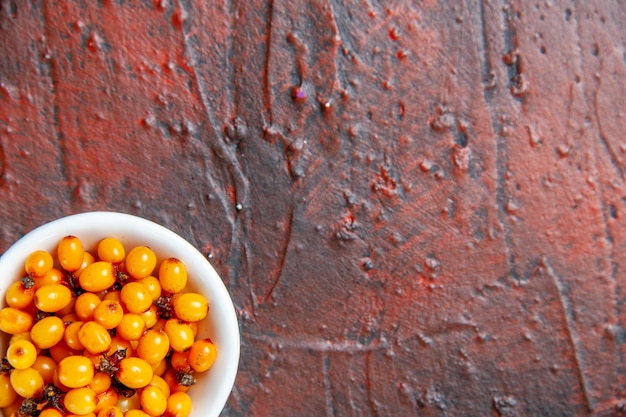 Free Photo top half view sea buckthorn in white bowl on dark red table copy space