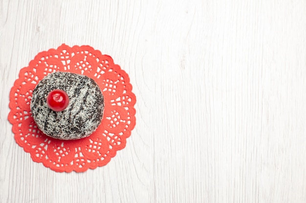 Free Photo top left side view cocoa cake with sour cherry on the red oval lace doily on the white wooden table