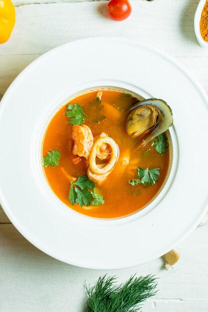 top  mussel soup with tomato and herbs in white bowl