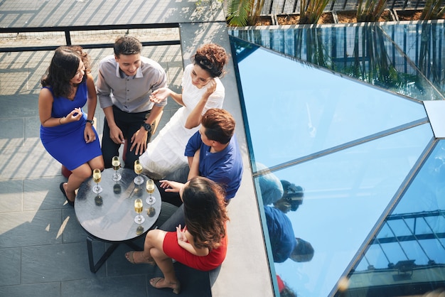 Free photo top shot of group of party guests sitting around table with drinks at outdoor terrace