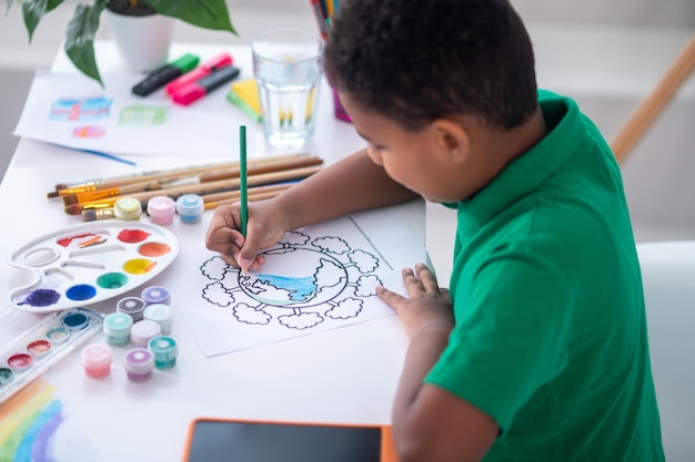 Free photo top and side view of dark-skinned boy painting indoors