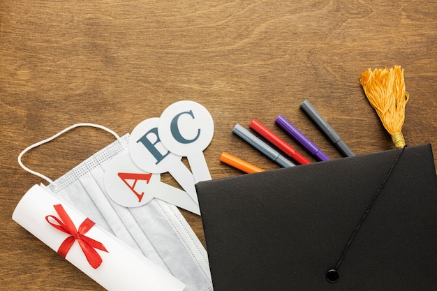 Free photo top view of academic cap with school supplies and medical mask