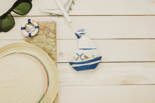 Free photo top view accessories to travel beach.vintage sailboat  with shell bicycle on wooden background.