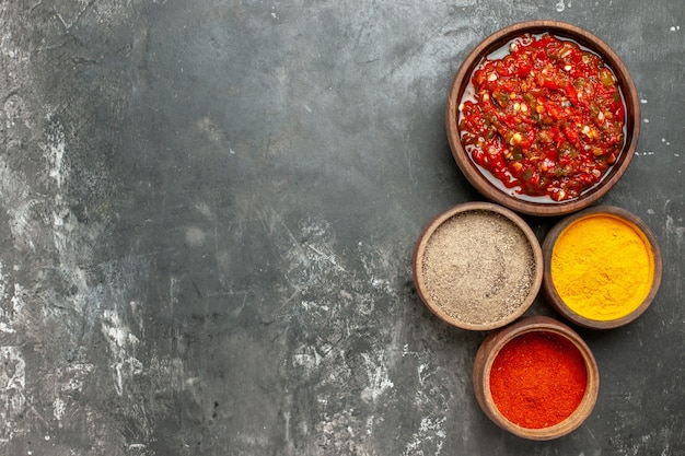 Free Photo top view adjika in wooden bowl different spices in small bowls on grey background