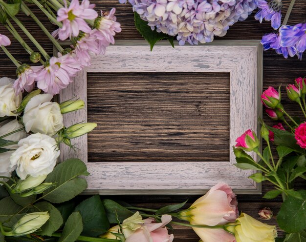 Top view of amazing flowers such as lilac roses daisy with leaves on a wooden background with copy space