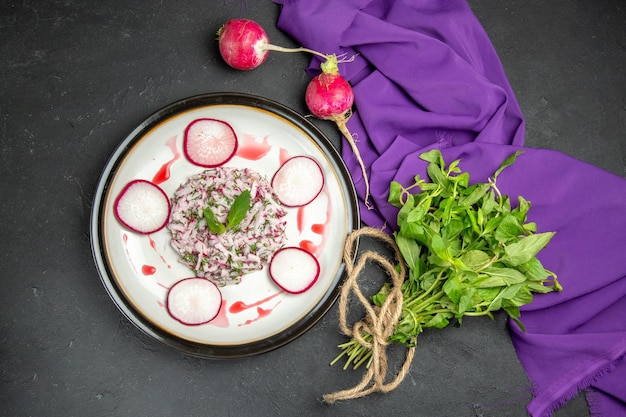 Top view an appetizing dish radish sauce on the plate herbs next to the purple tablecloth