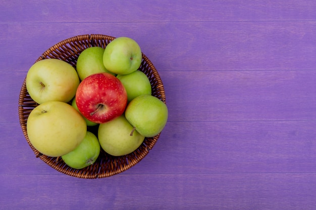 Free photo top view of apples in basket on purple background with copy space