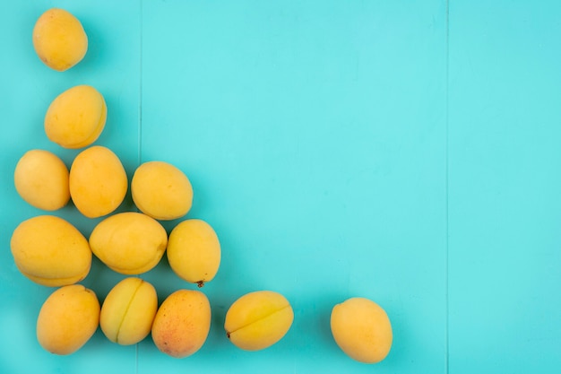 Top view of apricots in a bowl on a blue surface