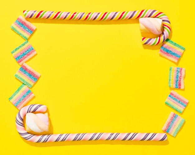 Top view arrangement of candies on yellow background with copy space