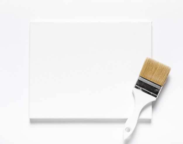 Top view arrangement with canvas and brush on white background