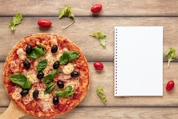 Top view arrangement with pizza and notebook