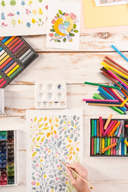 Top view of artist drawing flowers design at workplace