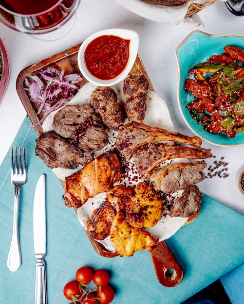 Top view of assorted meat kebab with onions spices and fresh salad