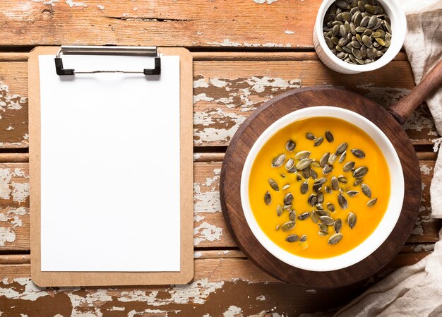 Free Photo top view of autumn squash soup with seeds and notepad