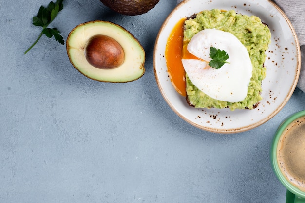 Top view of avocado toast on plate with poached egg and coffee cup