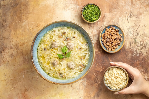 Free Photo top view azerbaijani erishte in bowl different stuffs in woman hand in bowls on beige background