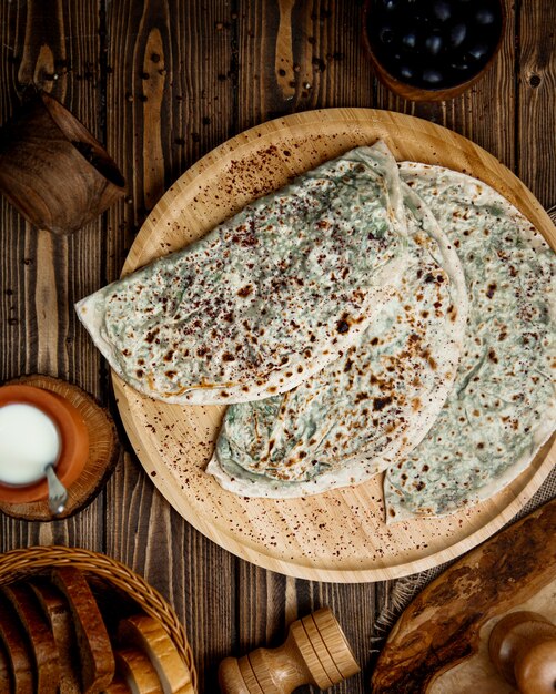 Top view of azerbaijani gutab stuffed flatbread with herbs served with yogurt