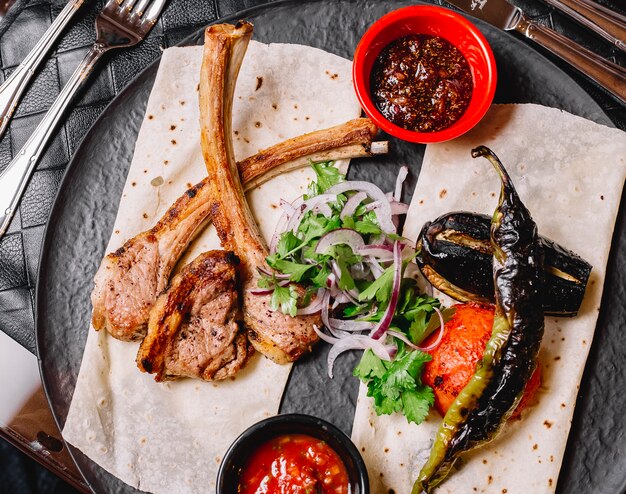 Top view of azerbaijani ribs kebab served with grilled vegetables on flatbread