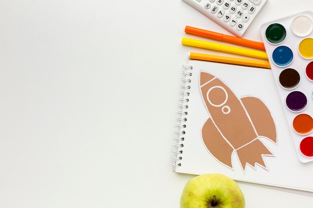 Top view of back to school essentials with notebook and watercolor