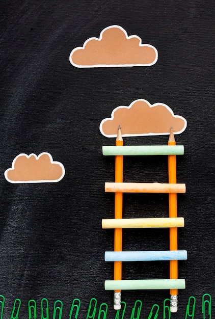 Free photo top view of back to school ladder with pencils and clouds