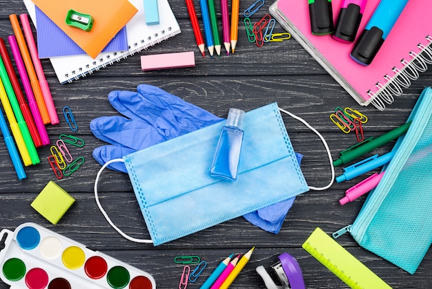 Top view of back to school stationery with medical mask and multicolored pencils