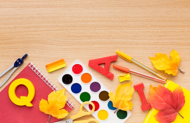 Free photo top view of back to school supplies with leaves and notebook