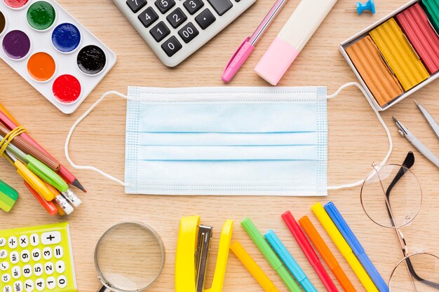 Top view of back to school supplies with medical mask and colorful mask