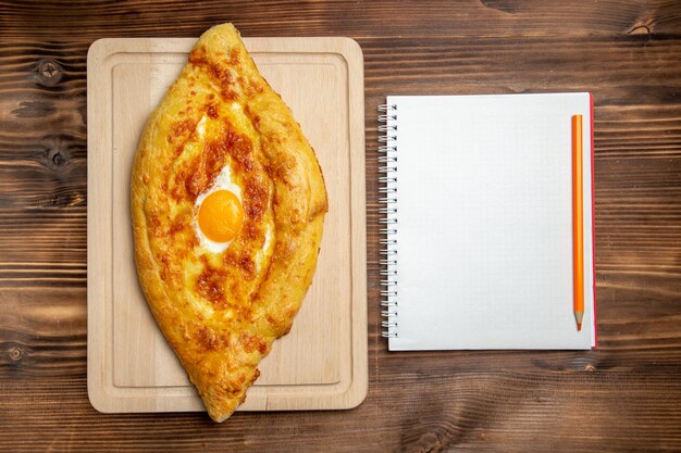 Top view baked bread with cooked egg on the wooden surface bread dough bun food breakfast