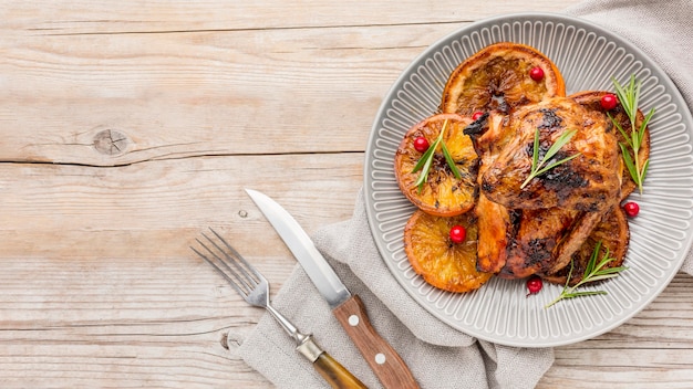 Top view baked chicken and orange slices on plate with copy-space