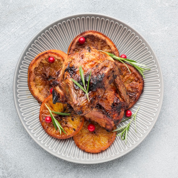 Free Photo top view baked chicken and orange slices on plate with herbs