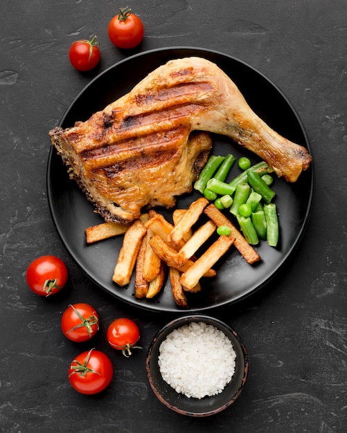 Top view baked chicken and potatoes on plate with tomatoes