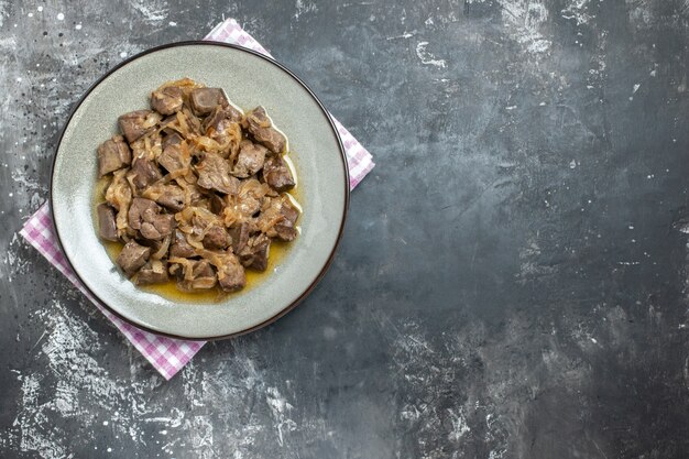 Top view baked liver and onion on oval plate on kitchen towel