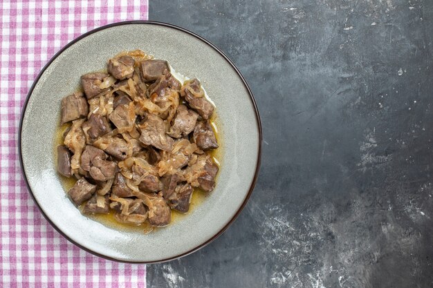 Top view baked liver and onion on oval plate on kitchen towel