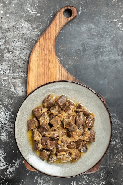 Top view baked liver and onion on plate on chopping board