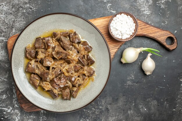 Top view baked liver and onion on plate sea salt on chopping board onions