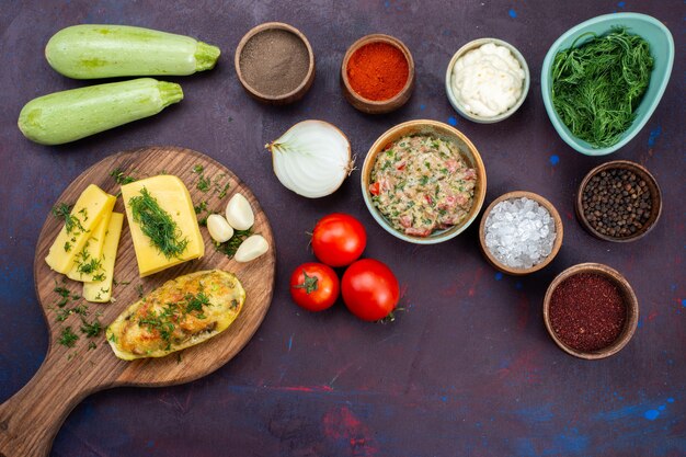 Free photo top view baked squashes with cheese greens minced meat and fresh vegetables on dark-purple desk.