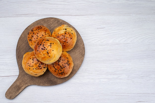 Top view baked tasty buns on the wooden desk and light background bun bread food meal