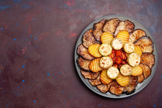 Top view baked vegetables potatoes and eggplants fresh off the oven on dark space