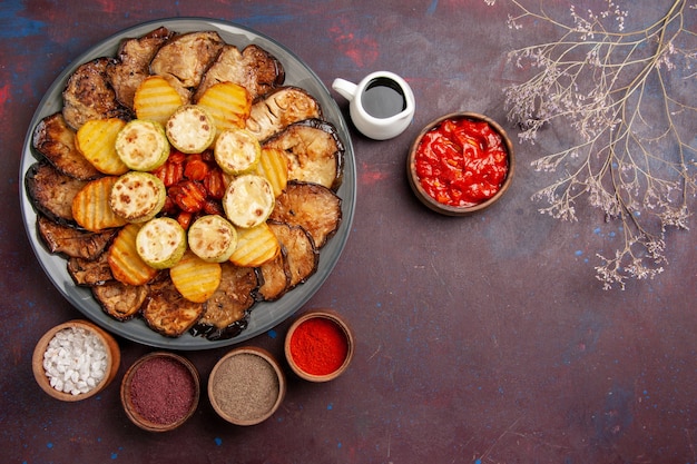 Free photo top view baked vegetables potatoes and eggplants with different seasonings on a dark space